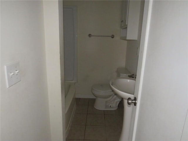 bathroom with baseboards, a sink, toilet, and tile patterned floors