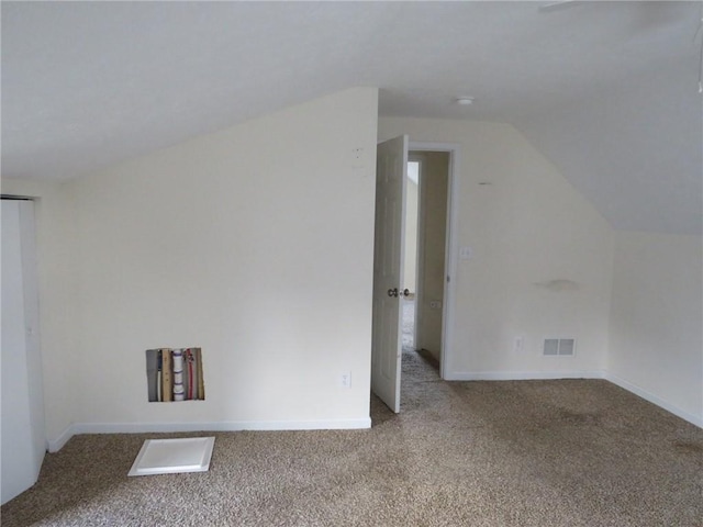 additional living space with baseboards, visible vents, vaulted ceiling, and carpet flooring