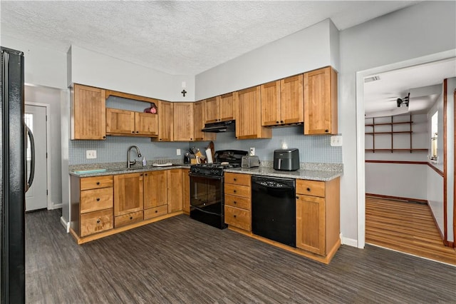 kitchen featuring tasteful backsplash, brown cabinetry, a sink, under cabinet range hood, and black appliances