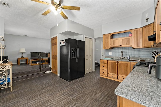 kitchen featuring visible vents, decorative backsplash, black fridge with ice dispenser, dark wood-style floors, and exhaust hood