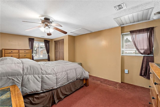 carpeted bedroom with attic access, visible vents, ceiling fan, and a textured ceiling