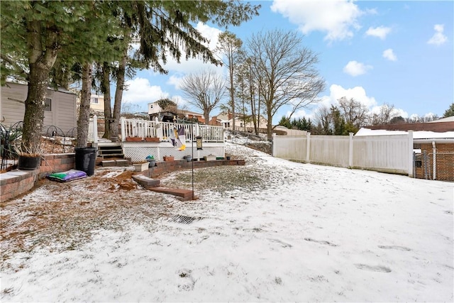 yard covered in snow with a deck and fence