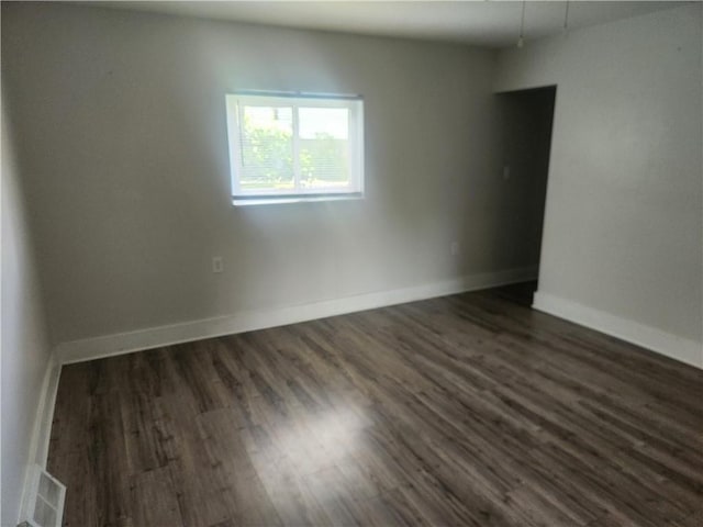 unfurnished room featuring baseboards, visible vents, and dark wood finished floors