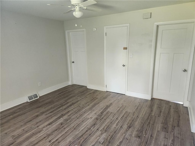 unfurnished bedroom featuring a ceiling fan, dark wood-style flooring, visible vents, and baseboards