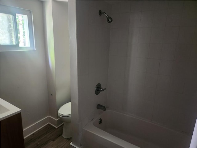 bathroom with toilet, vanity, shower / tub combination, wood finished floors, and baseboards