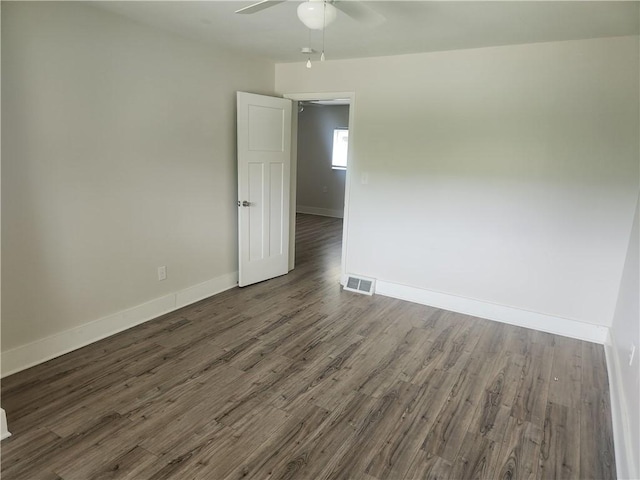 unfurnished room featuring dark wood-type flooring, visible vents, baseboards, and a ceiling fan