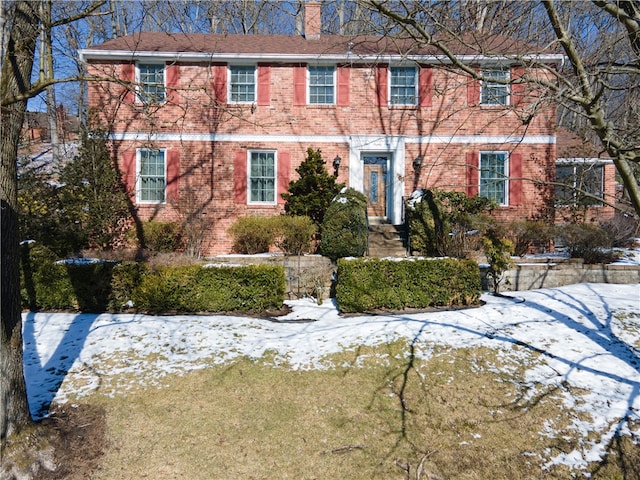 view of front facade featuring brick siding and a chimney