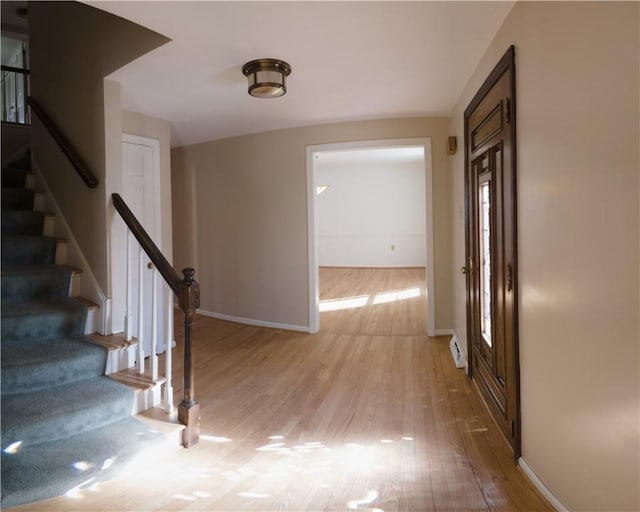 hallway featuring stairway, wood finished floors, and baseboards