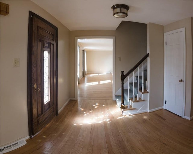 entryway featuring stairs, wood finished floors, visible vents, and baseboards