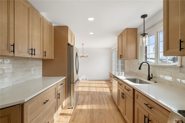 kitchen featuring stainless steel appliances, light brown cabinetry, a sink, and light countertops