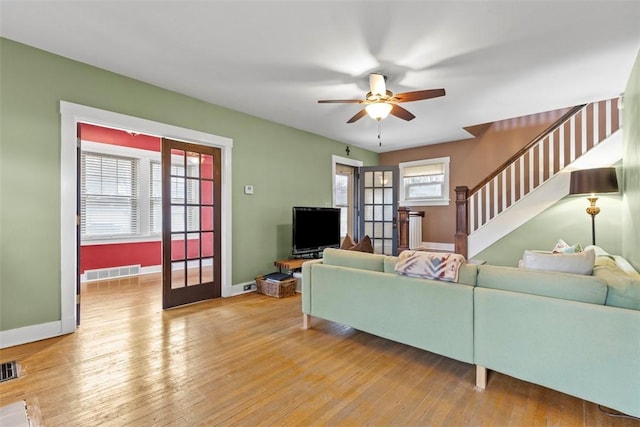 living area with light wood finished floors, stairway, visible vents, and baseboards