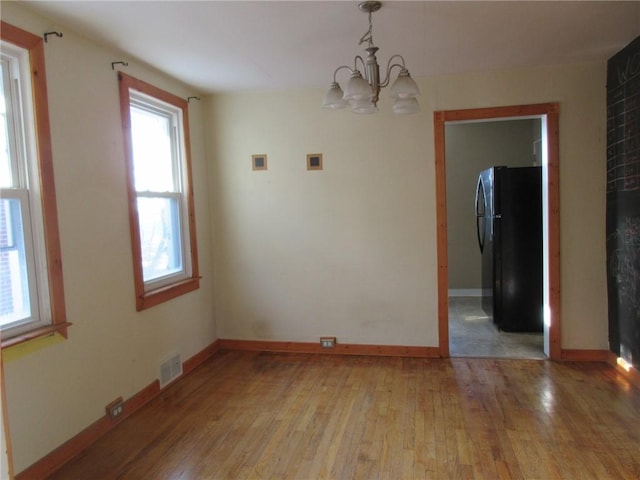 unfurnished dining area featuring light wood-type flooring, baseboards, and visible vents