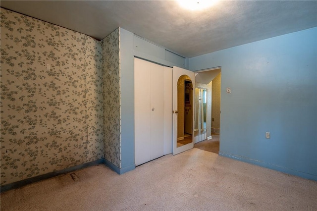 carpeted spare room with arched walkways