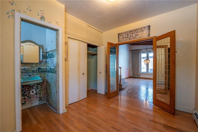 corridor featuring french doors, baseboard heating, and wood finished floors