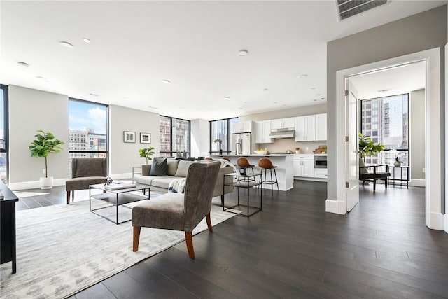 living area featuring dark wood-style flooring, visible vents, and baseboards