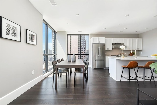 dining room featuring dark wood-style floors, a city view, visible vents, expansive windows, and baseboards