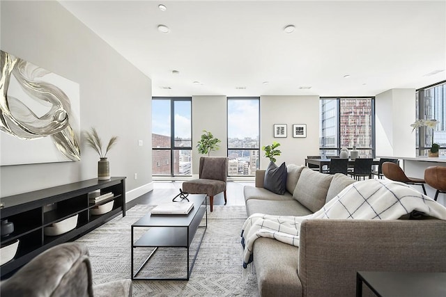 living area with a wall of windows, light wood-style flooring, and baseboards