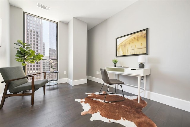 home office with floor to ceiling windows, visible vents, dark wood finished floors, and baseboards