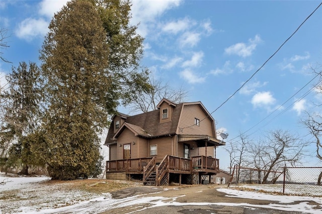 view of front of house with a deck, a shingled roof, fence, a gambrel roof, and stairway