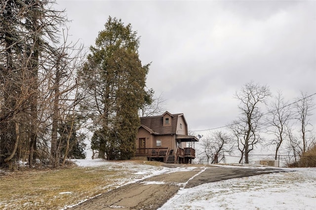 snow covered property with a deck and a gambrel roof