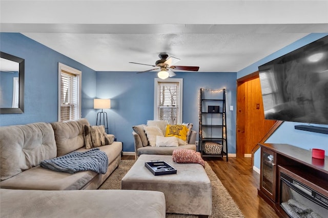 living room with dark wood-style floors, ceiling fan, and baseboards