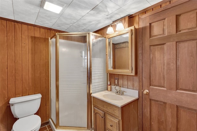 bathroom featuring toilet, wood walls, a shower stall, and vanity