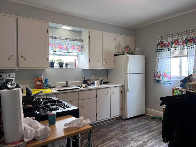 kitchen featuring dark wood-style floors, light countertops, freestanding refrigerator, and white cabinets