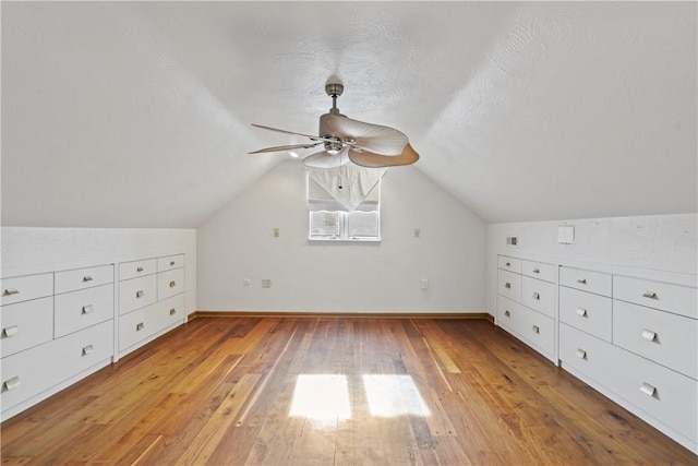 bonus room with a ceiling fan, vaulted ceiling, light wood-style flooring, and baseboards