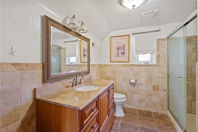 full bath featuring toilet, vanity, visible vents, tile walls, and a shower stall