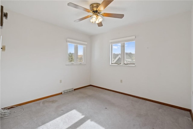 spare room with light carpet, baseboards, visible vents, and a ceiling fan