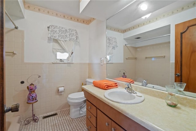 bathroom with toilet, vanity, visible vents, tile walls, and tile patterned floors