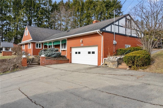 view of front of home featuring driveway, a garage, a shingled roof, a chimney, and brick siding