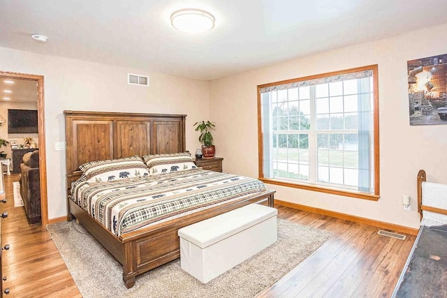 bedroom with light wood-style flooring, visible vents, and baseboards