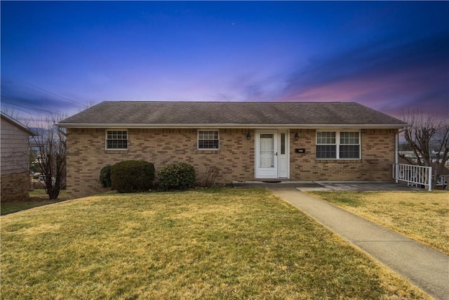 single story home with brick siding and a lawn