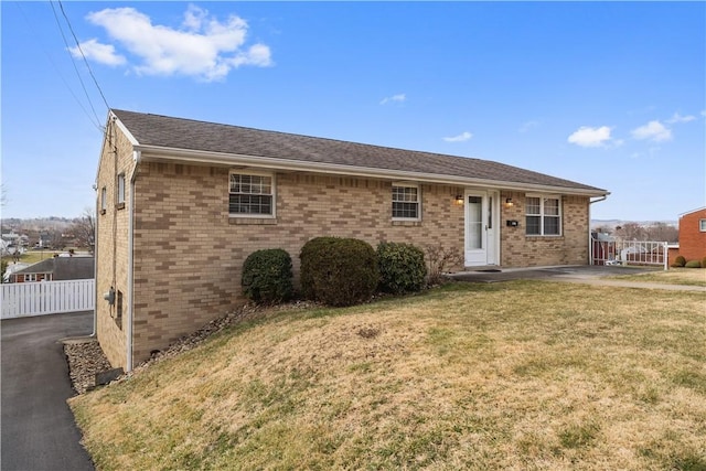 ranch-style home with brick siding, fence, and a front lawn