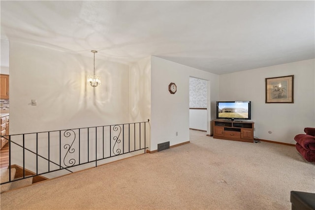 unfurnished living room with light colored carpet, visible vents, a notable chandelier, and baseboards