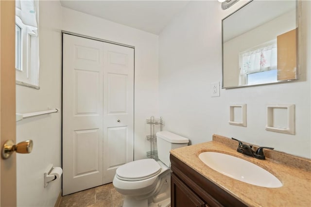 bathroom featuring a closet, stone finish floor, vanity, and toilet