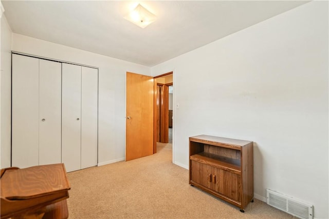 bedroom with light colored carpet, a closet, visible vents, and baseboards