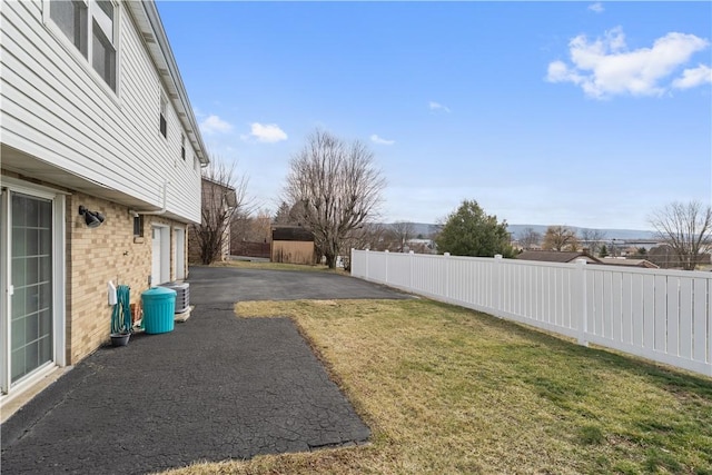 view of yard with a garage, a patio, cooling unit, and fence