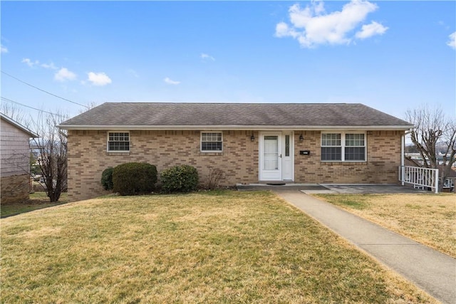 ranch-style home featuring brick siding, roof with shingles, and a front yard