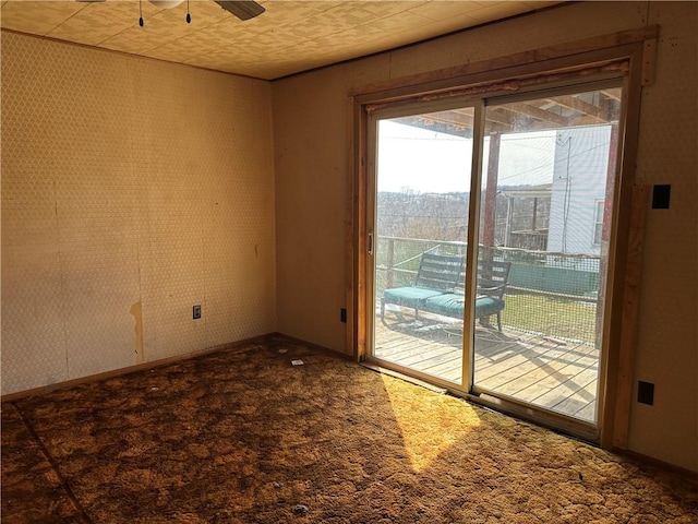 carpeted empty room featuring a ceiling fan, baseboards, and wallpapered walls