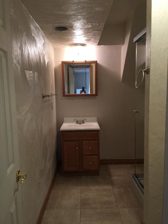 full bath with baseboards, a shower stall, vanity, and tile patterned floors