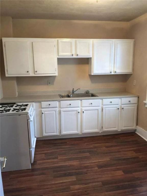 kitchen with dark wood-type flooring, white gas range, white cabinets, and light countertops