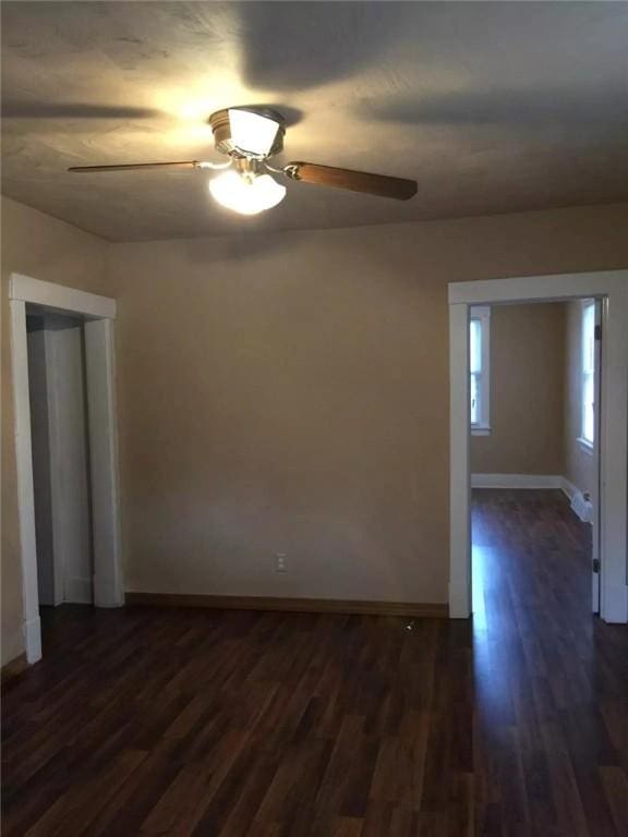 spare room featuring dark wood finished floors, baseboards, and ceiling fan