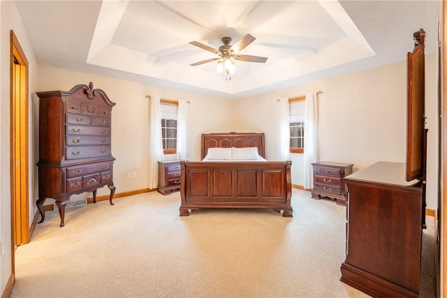 bedroom featuring a tray ceiling, light colored carpet, ceiling fan, and baseboards