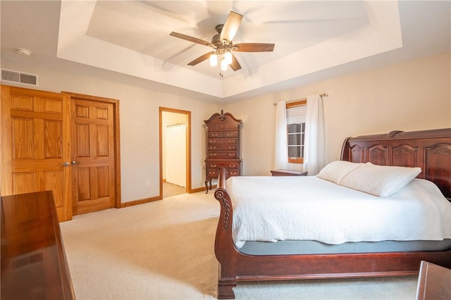 bedroom featuring light carpet, baseboards, visible vents, a raised ceiling, and a ceiling fan