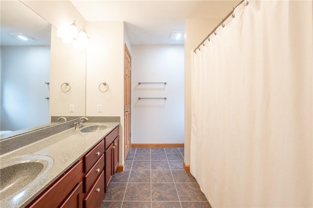 bathroom with double vanity, baseboards, a sink, and tile patterned floors