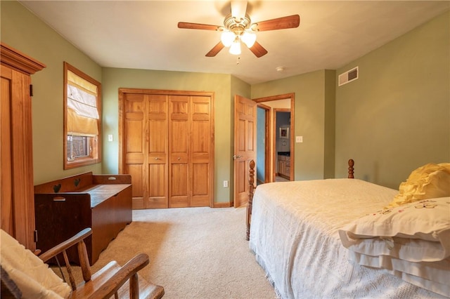 bedroom featuring a ceiling fan, a closet, visible vents, and light colored carpet