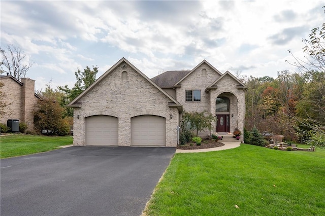 french country home featuring a garage, a front lawn, aphalt driveway, and brick siding