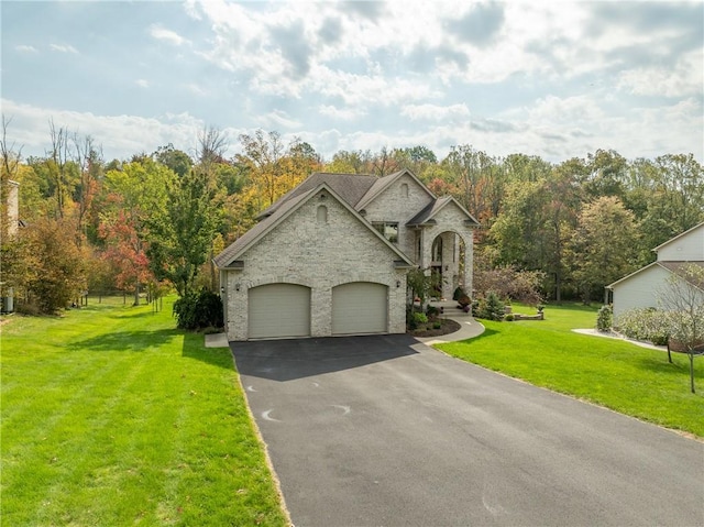 french provincial home with a garage, stone siding, a front lawn, and aphalt driveway